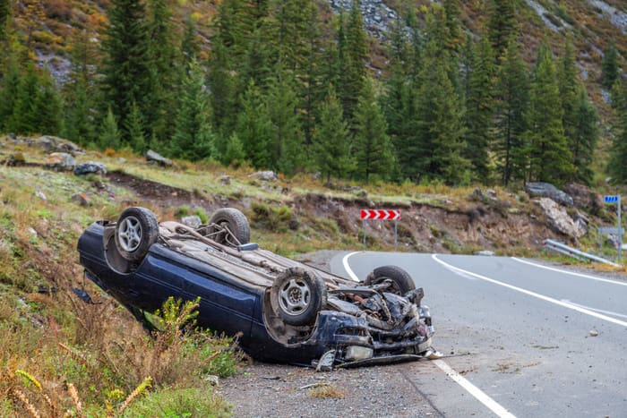 Car accident place on a bend, overturned car lies on the roof,