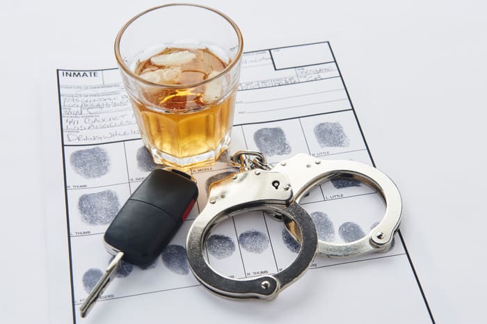 Handcuffs with fingerprints keys and glass of alcohol on ice