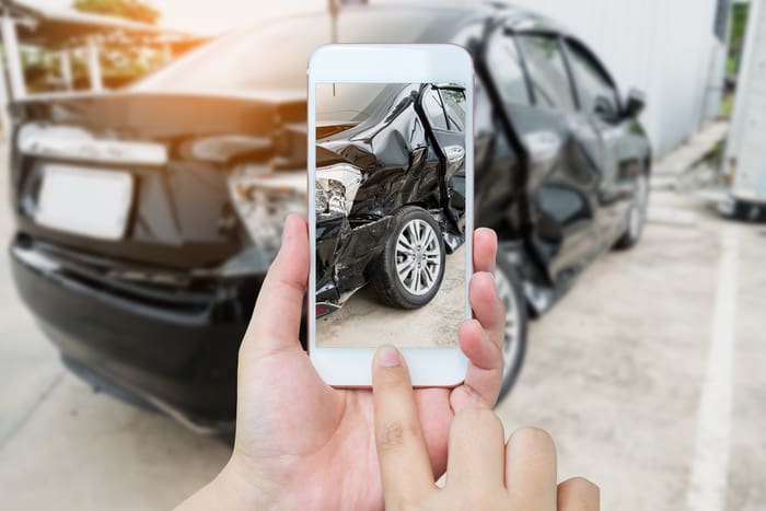 female hold mobile smartphone photographing car accident for insurance