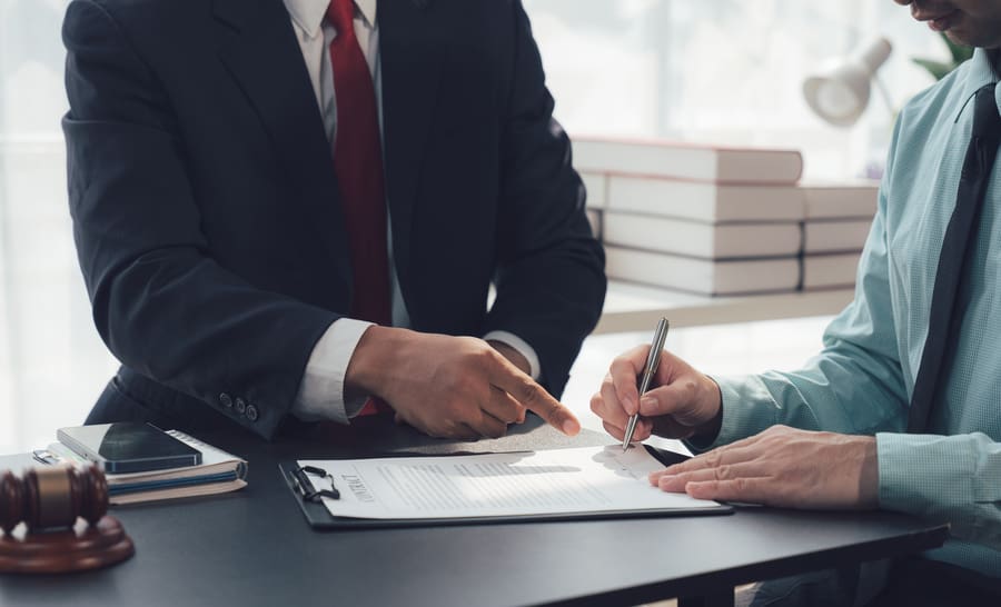 An attorney points to the signature line to a client