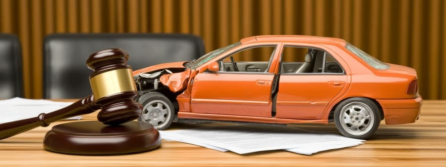 gavel and broken car model with a lawyer drafting documents, representing legal services, insurance claims, and vehicle accident.