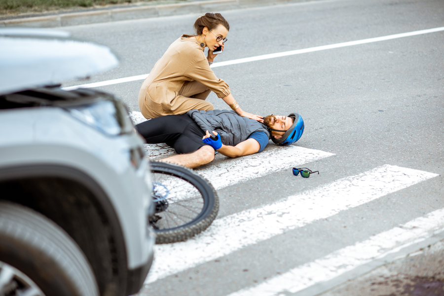 hit and run accident - Road accident with injured cyclist lying on the pedestrian crossing near the broken bicycle, worried woman driver calling and checking mens pulse