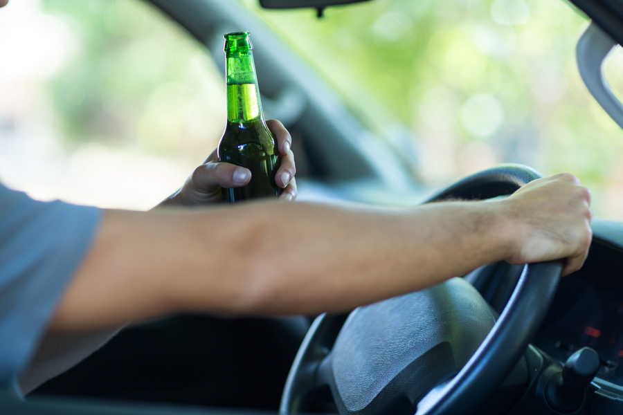 Cropped hands of a young man with alcohol while sitting in car