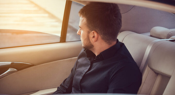 a businessman sitting on rear seat of a car