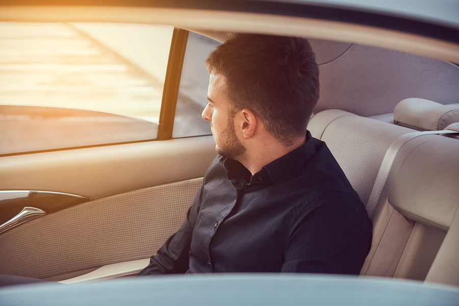 a businessman sitting on rear seat of a car