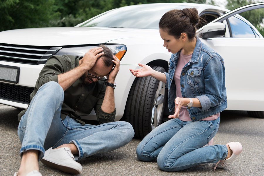 driver sitting near man on road after car accident