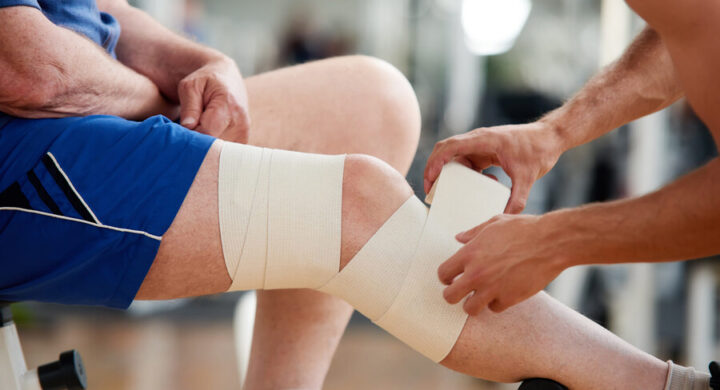 Senior man with bandage on leg after injury in an event